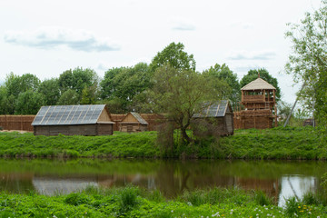 Ancient authentic wooden houses in Belarus, a cloudy day, calm river in landscape.