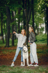 Fototapeta premium Beautiful girl in a white blouse. Women in a summer forest. Ladies with a dog