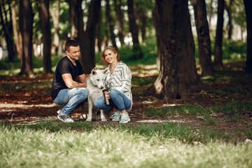 Fototapeta premium Couple in a forest. Pair playing with a cute dog