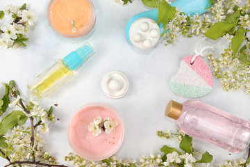 Spa ingredients, a set of cosmetic oils and creams for skin and body care on a gray background with branches of blooming cherry. Shopping concept and modern woman, sale, selective focus