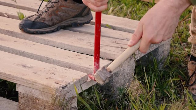 a man disassembles pallets with a crowbar and hammer