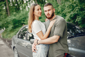 Couple in a forest. Man in a green t-shirt. Pair near car