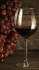Glass glass of red wine on a background of grapes