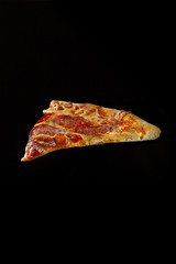 Slice of pepperoni pizza on a black background