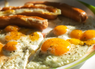 Close up of fried chiken and quail eggs with grilled suasage in the sunny morning.Breakfast plate.