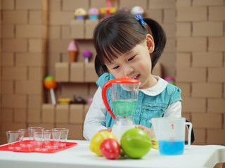 toddler girl pretend play food preparing role against cardboard blocks kitchen background