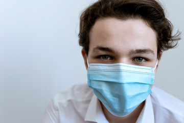 man in a medical mask with medical gloves on a white background, face of a man, a doctor in a blue medical mask on a white background