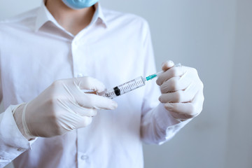 doctor in white gloves holding a syringe