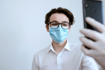 man in a medical mask with a phone in his hands, communicating during quarantine