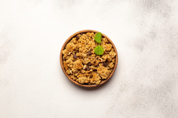 Wooden bowl with Granola with fresh mint leaf on light background.Healthy food concept.Top view with copy space.