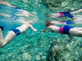 A boy and a teenage girl snorkeling and exploring coral reef under the underwater surface with...