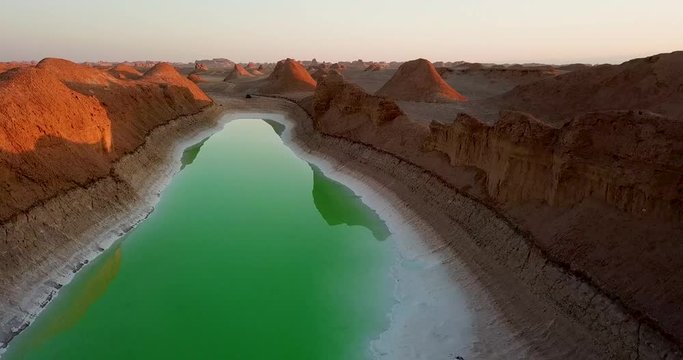 Camping Beside a beautiful green lake with shadow and reflection in middle of desert kalouts, hills and rocks landscape at sunset daytime