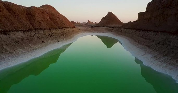 Aerial move forward to setup tent camping close to the green lake in the desert in Shahdad Kerman Iran at sunset golden time