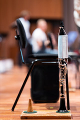 A face mask haning on a clarinet that is placed on a stand on stage representing performance...