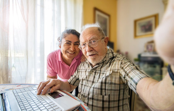 Elderly man with her caregiver taking a selfie photo at home