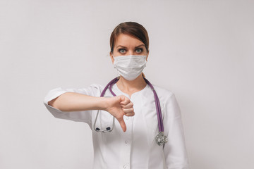 A young female doctor in a medical mask shows that everything is in order.