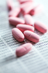 Pills scattered on paper with DNA data. Small depth of field.