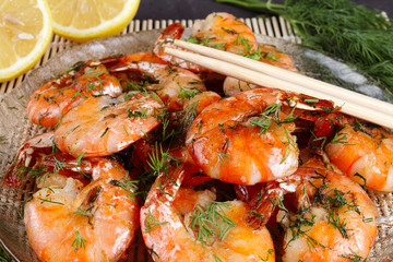 fried king prawns in a plate on a bamboo mat, lemon, dill, close-up