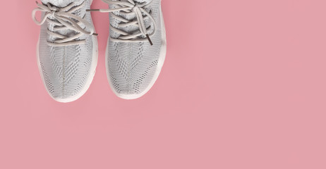 New comfortable sneakers, gray sports shoes with laces on a colored pink background with copy space. Fashion Stylish, beautiful women's shoes for women and teenagers. Minimalism. Flat lay, nobody