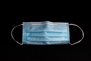 close-up of a blue surgical mask isolated on black background