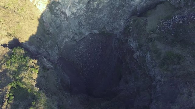 Top down view of a deep hole with rocks landslides caused by an earthquake or volcanic eruption, aftermath. Volcano crater hole aerial view.