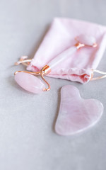 Pink Gua Sha facial massage tools. Rose Quartz jade roller on pink background. Anti age, lifting and toning treatment at home. Copy space.