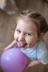 Fototapeta na wymiar cheerful little girl with balloon in her hands laughs and shows her tongue.