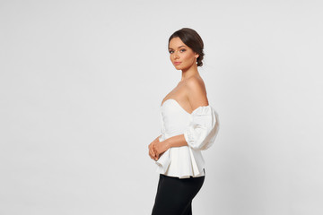 Young beautiful stylish pretty woman with makeup and hair in a bun in white top and black skirt...