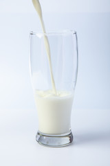 Pouring milk in a glass isolated against White background