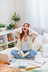 Cute teen girl holding her head and screaming, tired of e-learning.
