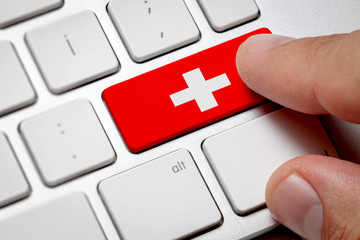 Online International Business concept: Computer key with the Switzerland on it. Male hand pressing computer key with Switzerland flag.