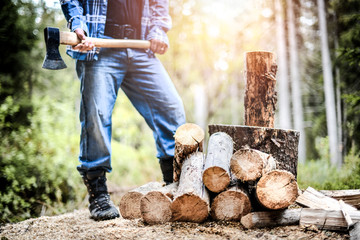 Man holding heavy ax. Axe in strong lumberjack hands chopping wood trunks