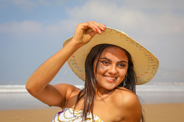 Beautiful young girl in a hat on the ocean.