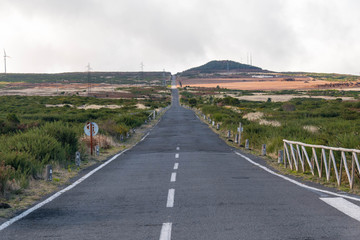 A dead straight empty road in a rugged volcanic island. This road passes the Paul de Serra ecological park in Madeira, Portugal