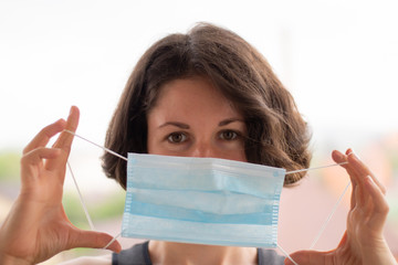 Girl in a blue medical mask looks at the camera