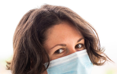 Girl in a blue medical mask looks at the camera