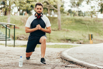 Man wearing sportswear doing squats in public park.