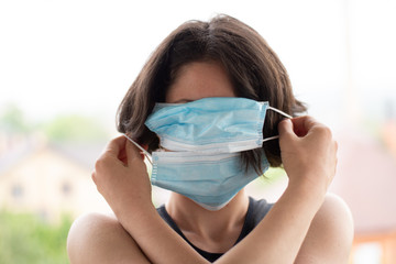 Girl in a blue medical mask looks at the camera