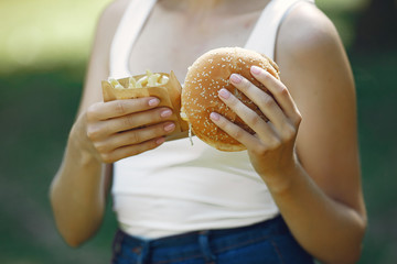 Beautiful girl in a summer park. Lady with a burger