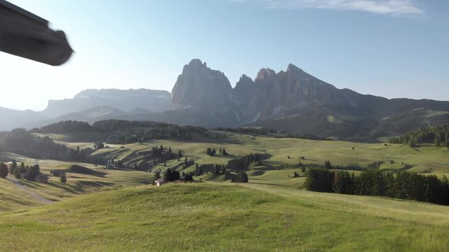 Man hiker walking on balcony of a traditional wooden mountain hut at Alpe di Suisi meadows Dolomites, northern Italy. Idyllic morning at Seiser Alm valley in South Tyrol Alps