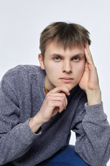 A young man poses barefoot on a white background. Looks at the camera