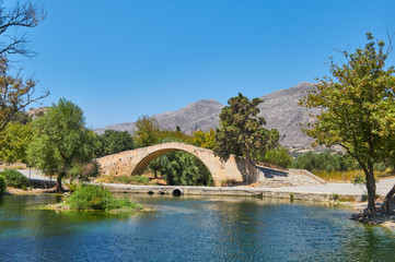 Fototapeta na wymiar roman bridge in preveli vale behind a lagoon, crete island hills in the background