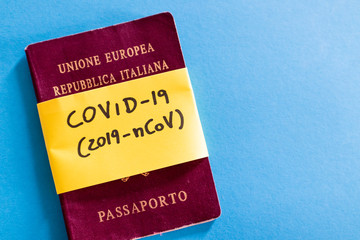 coronavirus covid-19 yellow label on an Italian passport on a light blue background. Controls on travel and tourism in crisis. ban on expatriation. Summer 2020 tourism in Italy