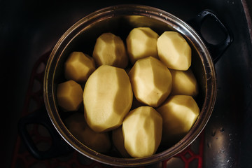 large peeled potatoes in a silver pot. Clean potatoes for cooking. Dishes with peeled potatoes.the view from the top