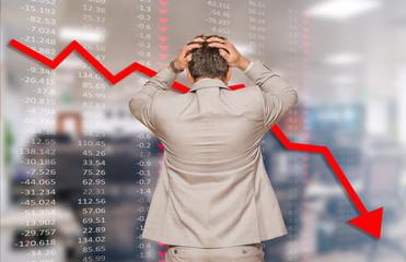 Back view of middle age businessman pulling his hair out as his business falling during recession,...