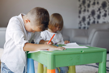 Brother and sister in a playing room. Children drawing at the table