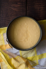 Cake batter in a pan. Wooden background