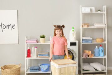 Cute little girl doing laundry at home