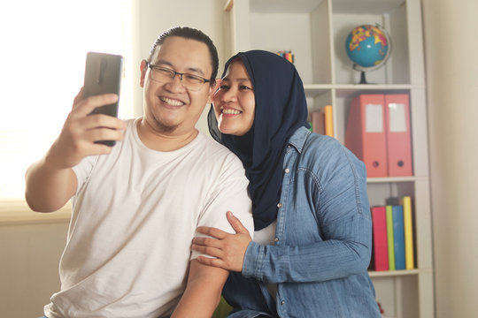Happy Asian Muslim Couple, Taking Selfie Picture on Smart Phone