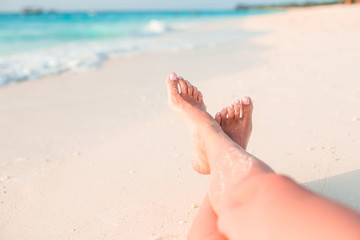Fototapeta na wymiar Woman's feet on the white sand beach in shallow water